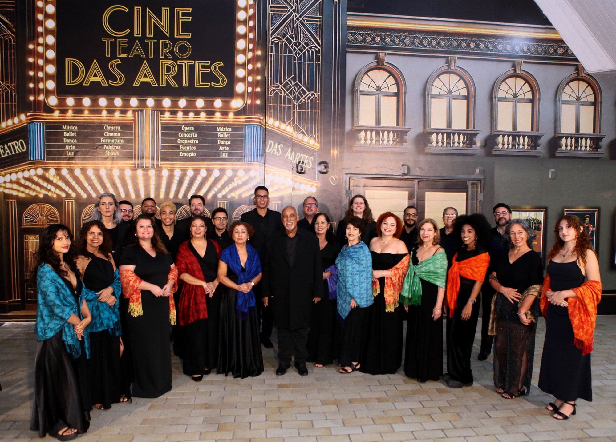 Coral Opus Liberi em traje de concerto diante do painel do Cine Teatro das Artes