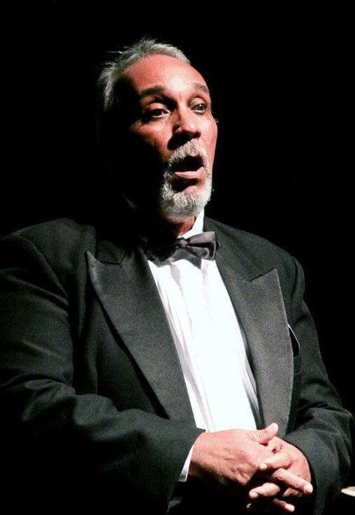 Maestro Cláudio Modesto, de smoking, cantando em um palco